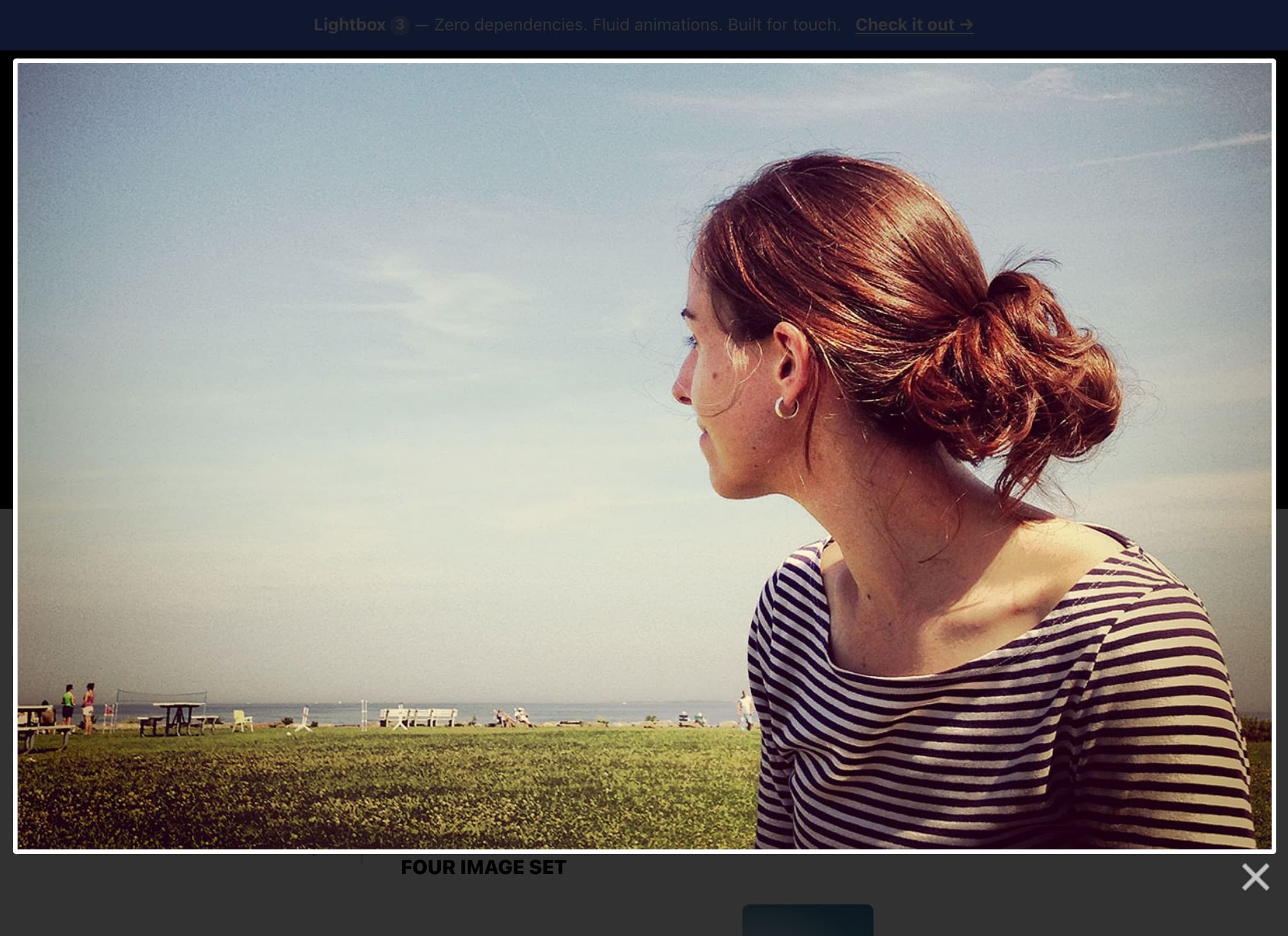 The Lightbox2 demo site photographed in 2026 with the lightbox open: a photo of a woman looking out over a park, a Four Image Set caption, a close button, and a banner advertising Lightbox 3 as zero dependencies, fluid animations, built for touch